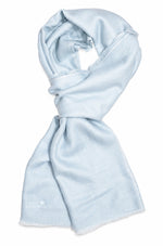 A light blue scarf with a soft, lightweight texture and frayed edges, styled in a loop on a plain white background. 