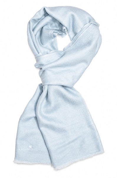 A light blue scarf with a soft, lightweight texture and frayed edges, styled in a loop on a plain white background. 