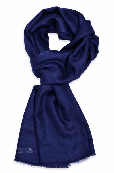 A dark navy blue scarf with a soft, silky texture and fringed edges, styled in a loop on a plain white background. 