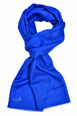 A vibrant royal blue scarf, styled in a loop with fringed edges